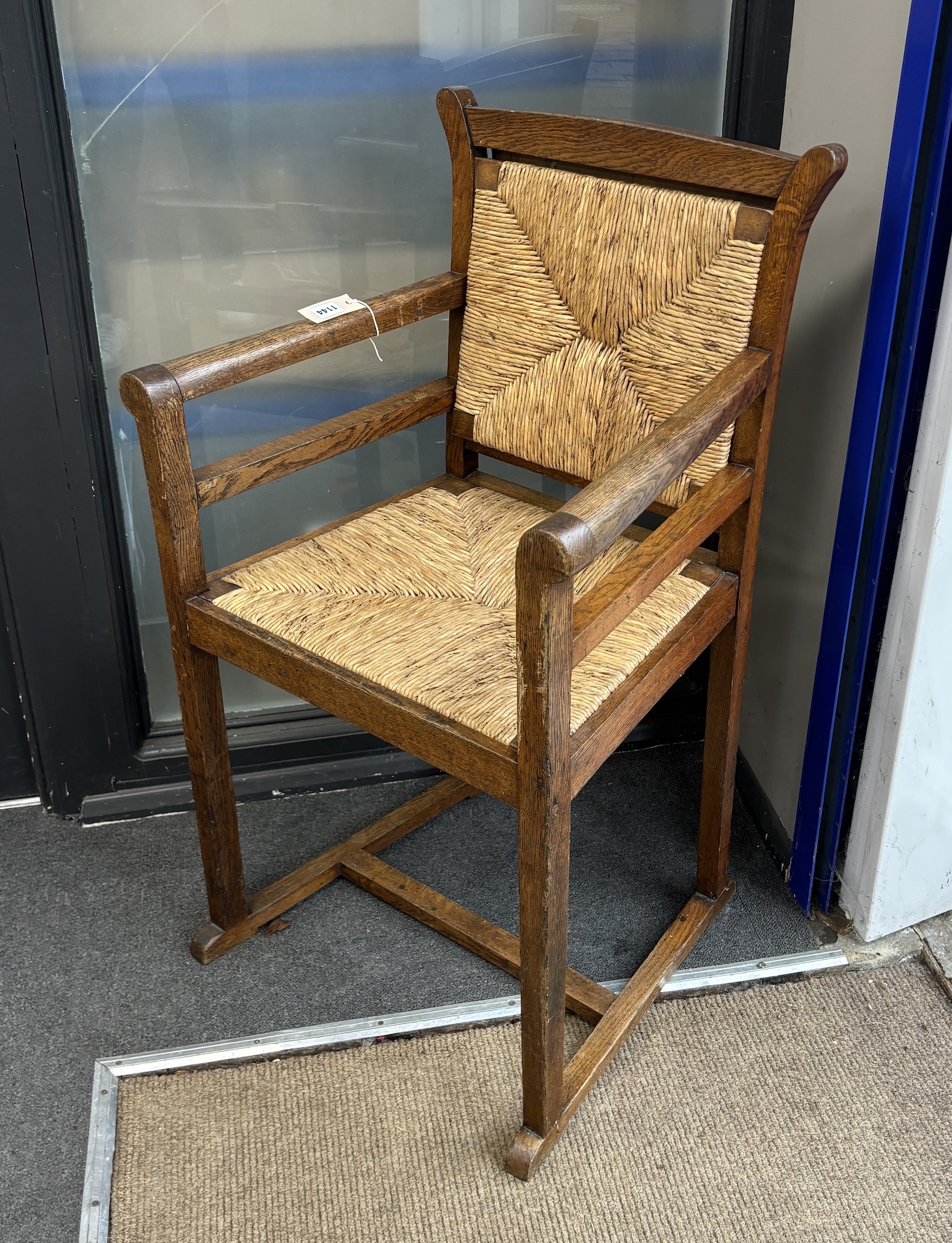 An early 20th century Arts and Crafts rush seat and back oak elbow chair, width 57cm, depth 48cm, height 99cm